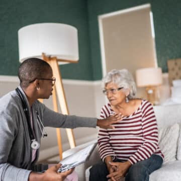 How Your HVAC Equipment Protects Against Viruses. Doctor talking to a senior woman in the bedroom.